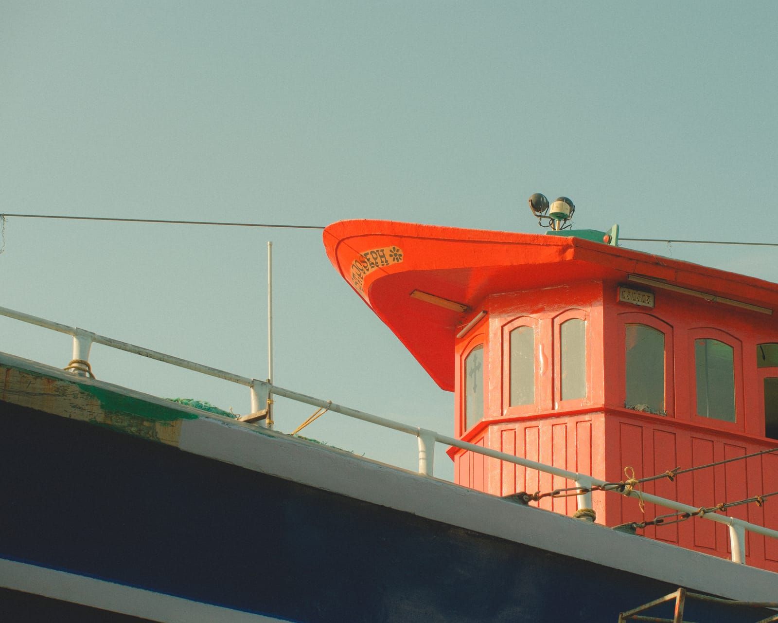 The bright red wheelhouse of a moored fishing boat against a pale sky.